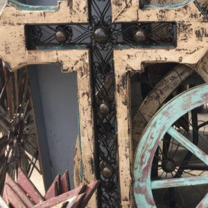 A cross with metal accents and wheels in the background.