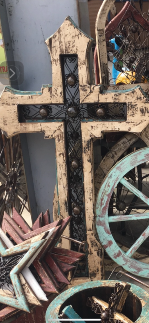 A cross with metal accents and wheels in the background.