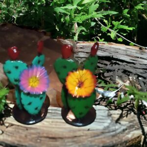 Two cactus figurines sitting on top of a log.