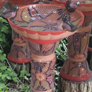 A bird bath made of clay with flowers painted on it.