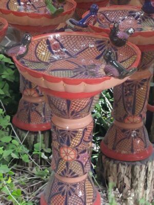 A bird bath made of clay with flowers painted on it.